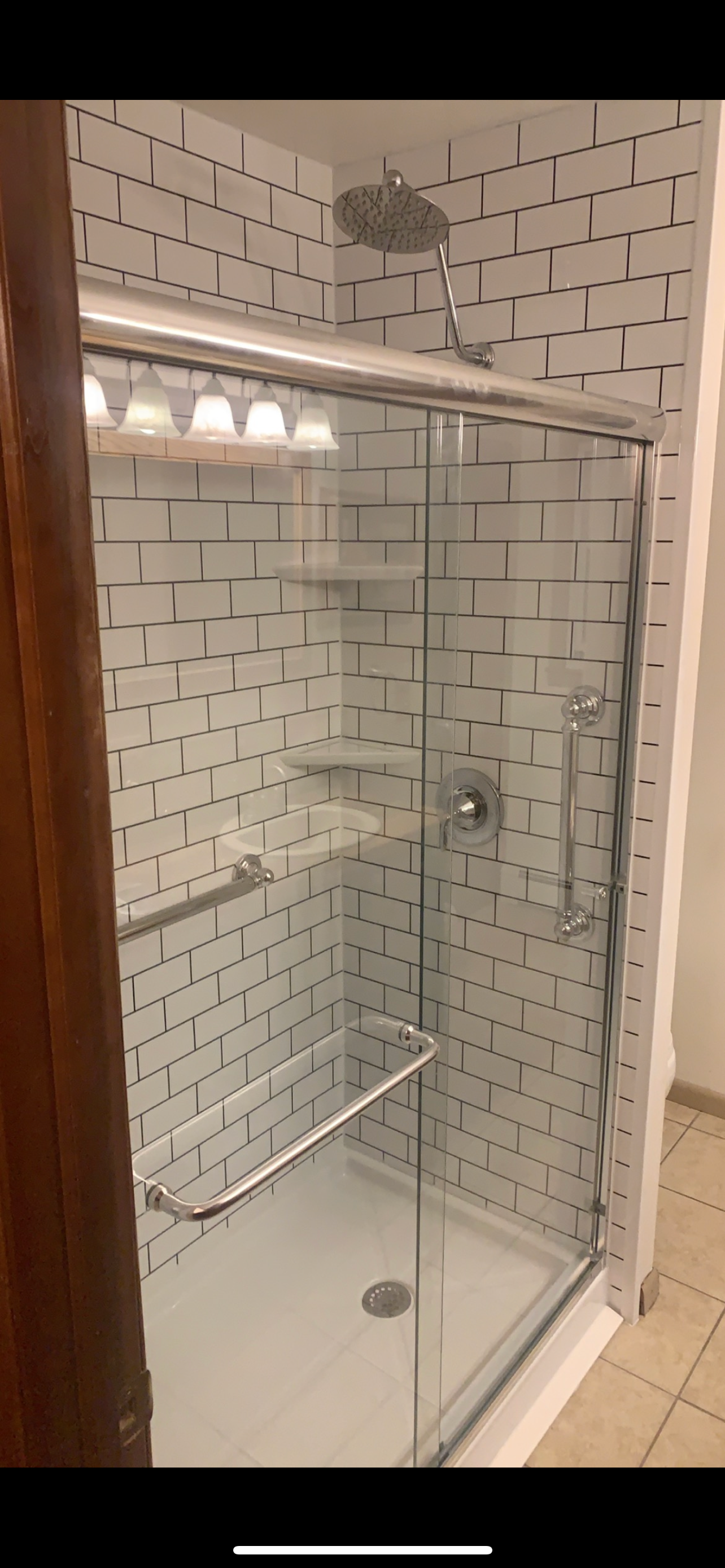 Tub and shower combination with black fixtures and marble walls in Wisconsin